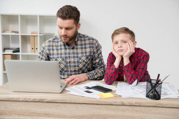 istock Businessman freelancer working at table with son at home office 687479636