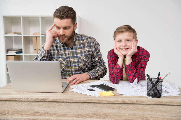 istock Businessman freelancer working at table with son at home office 687482938