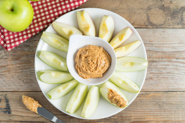 Green apple sliced with peanut butter. Top view. Green apple sliced with peanut butter. Top view. dipping stock pictures, royalty-free photos & images