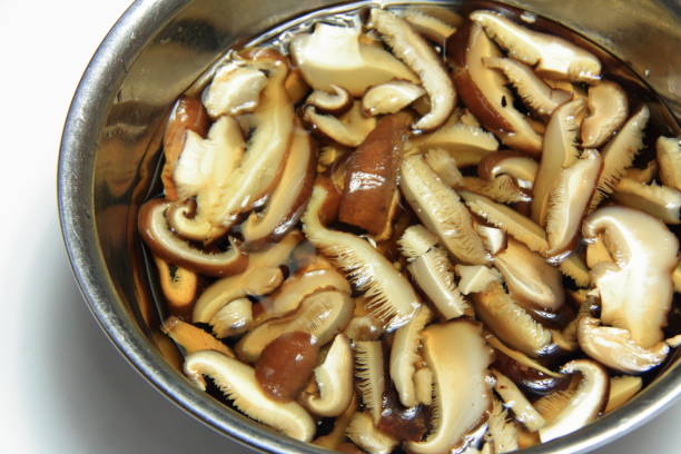 замочите тонкие нарезанные сушеные грибы шиитаке в воде - shiitake mushroom edible mushroom mushroom dry стоковые фото и изображения