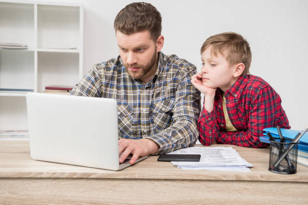 istock Businessman freelancer using laptop with son at home office 687486710