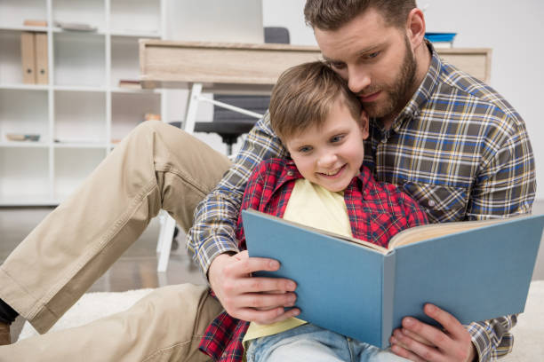 istock Businessman freelancer reading book with son at home office 687487636