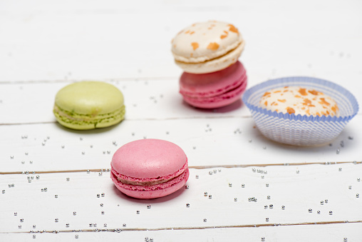 Group of beautiful colorful macarons on white wooden table.