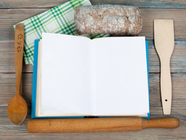 istock Open recipe book on wooden background, spoon, rolling pin , green checkered tablecloth 687502340