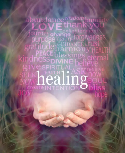 Female cupped hands with the word 'healing' floating above surrounded by a word cloud of healing related words on a swirling misty energy background