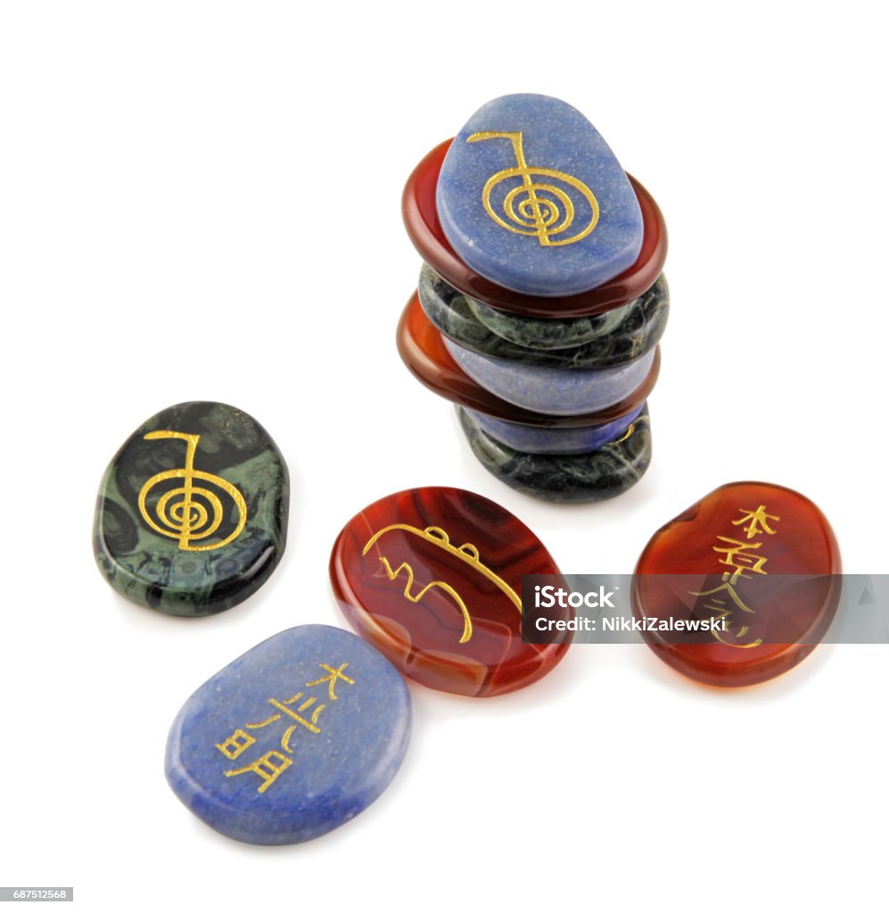 Reiki Meditation Stones Three sets of Reiki Symbols etched in gold onto semi-precious carnelian, agate and aventurine oval flat stones on a white background Reiki Stock Photo