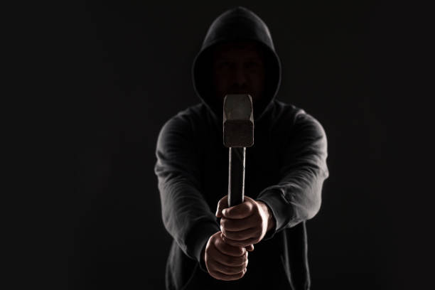 Criminal in dark clothes and balaclava with hammer