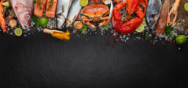 Whole lobster with seafood, crab, mussels, prawns, fish, salmon steak, mackerel and other shells served on black slate stone