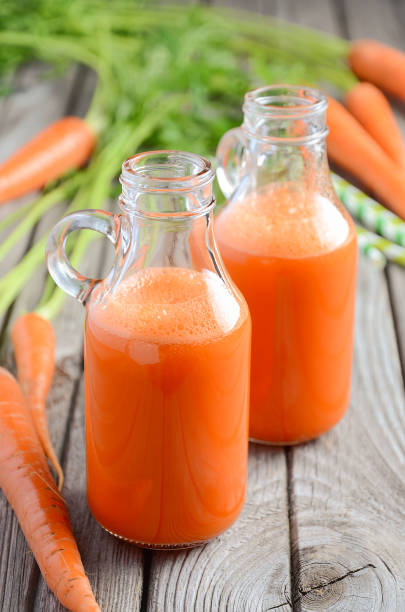 istock Fresh carrot juice in a bottles on rustic wooden background 687520862