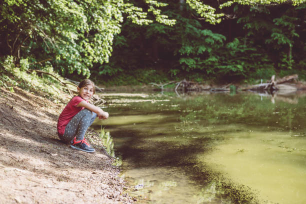 istock Girl squatting by the lake 687533984