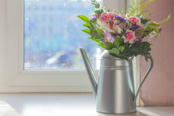 still life flowers in watering can on the windowsill