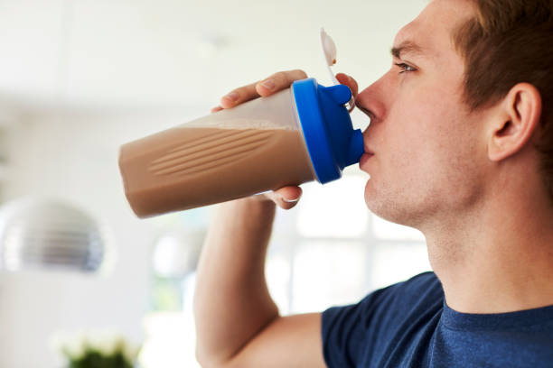Man Drinking Protein Shake In Kitchen At Home Man Drinking Protein Shake In Kitchen At Home protein drink stock pictures, royalty-free photos & images