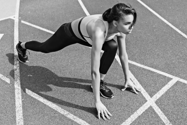 istock Concentrated athletic young runner on starting line at running track stadium, black and white photo 687549646