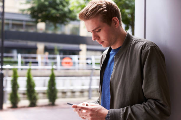 istock Man Sending Text Message On Mobile Phone In Urban Setting 687552814