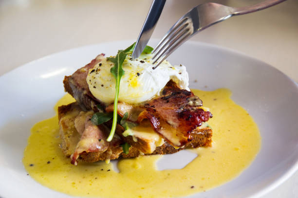 istock Cutting a delicious gourmet eggs benedict breakfast with knife and fork 687559236