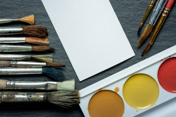 istock brush, paint white sheet of paper on a dark background 687559762