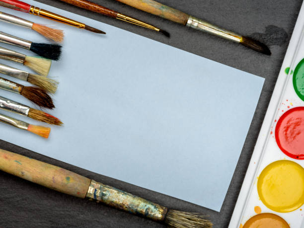 istock brush, paint white sheet of paper on a dark background 687559784