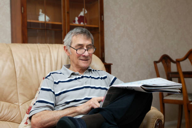 istock Retired man sat in his living room reading newspaper 687560526
