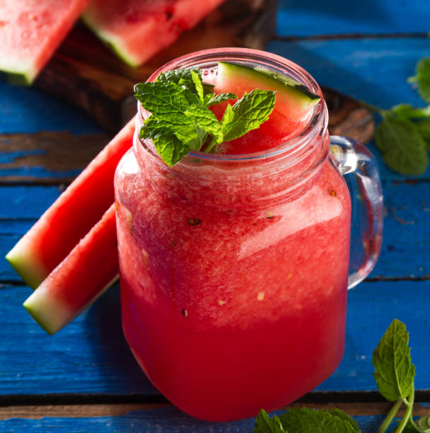 istock Tasty fresh appetizing watermelon drink smoothie with mint on blue table. Closeup. 687564216