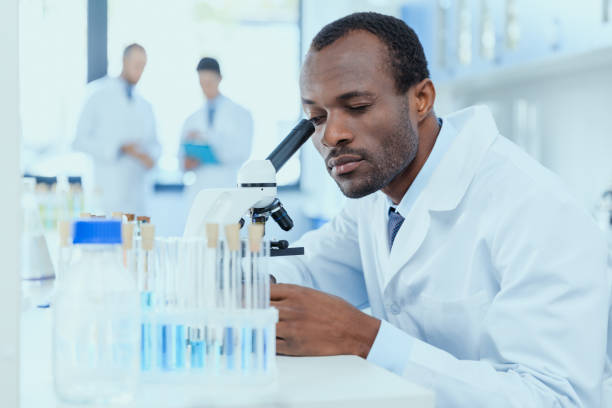 cientista afro-americano de jaleco branco trabalhando com microscópio em laboratório, conceito de pesquisador de laboratório - separating laboratory - fotografias e filmes do acervo
