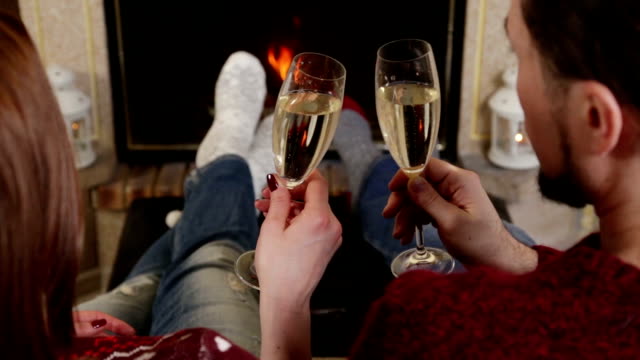 Couple toasting of champagne together near fireplace