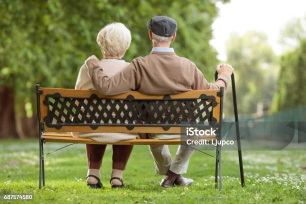 Pareja De Ancianos Sentada En Un Banco De Madera En El Parque Foto de stock y más banco de imágenes de Tercera edad