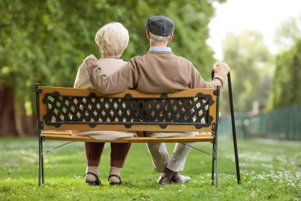 Photo of Senior couple sitting on a wooden bench in the park