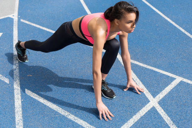 istock Concentrated athletic young runner on starting line at running track stadium 687574710