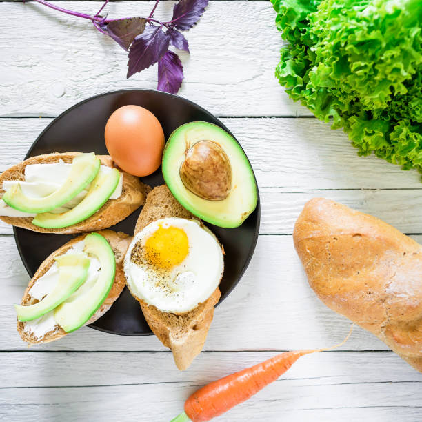istock Sandwiches with avocado and eggs on a black plate on rustic table. Flat lay. Top view. Tasty breakfast 687593670