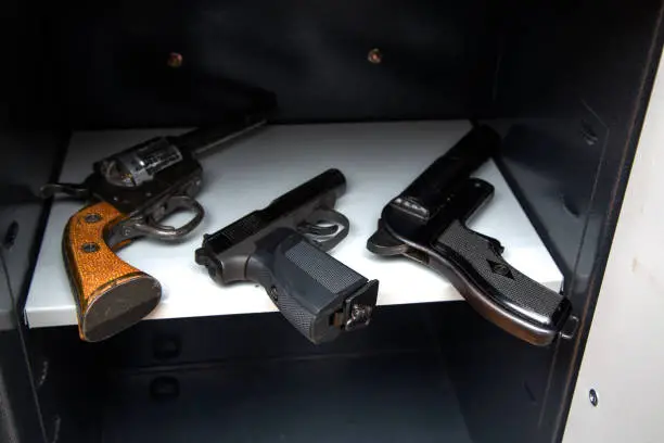 Three combat pistols on a shelf in an open safehree pistols in the open safe