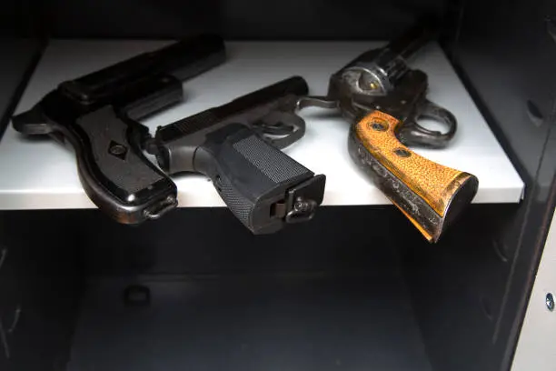 Three combat pistols on a shelf in an open safehree pistols in the open safe