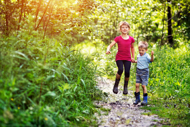 istock Brother and sister jumping on muddy forest path 687596118