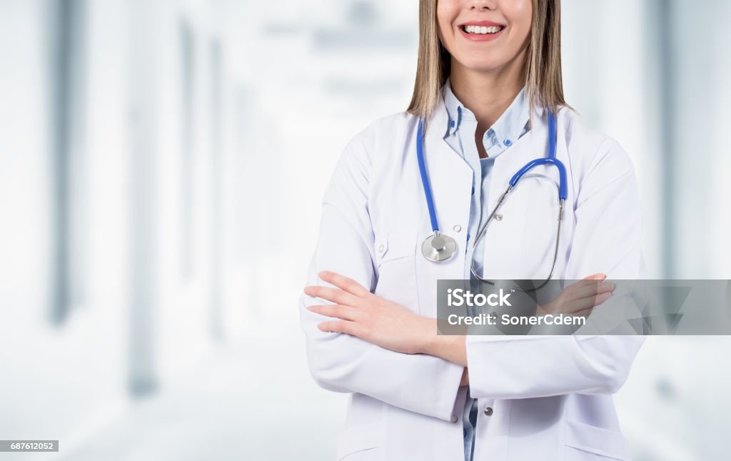 Seguro médico sonriente posando con los brazos cruzados en el hospital - Foto de stock de Abrigo libre de derechos