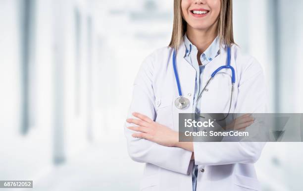 Seguro Médico Sonriente Posando Con Los Brazos Cruzados En El Hospital Foto de stock y más banco de imágenes de Abrigo