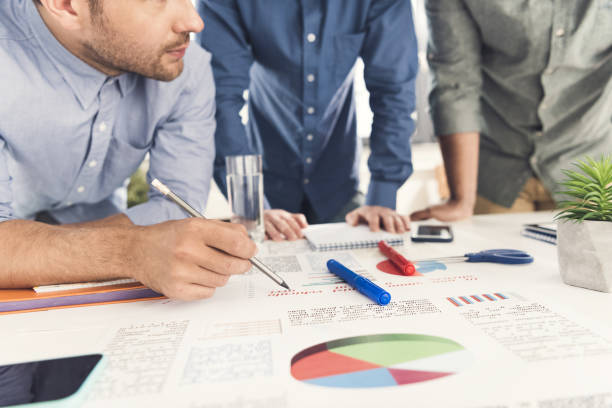 istock Three young businessmen leaning at table and working at project together, business teamwork 687613530