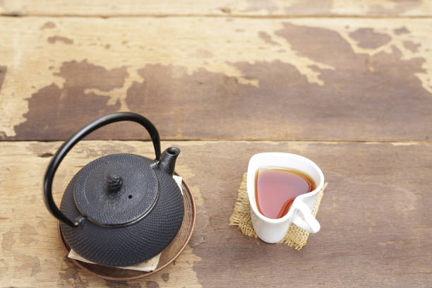 istock Black kettle and white tea cup on wooden table 687637094