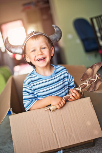 istock Little boy playing viking in cardboard box boat 687639210