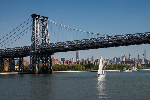 Sailboat passes under the Williamsburg bridge that connects Manhattan with Brooklyn