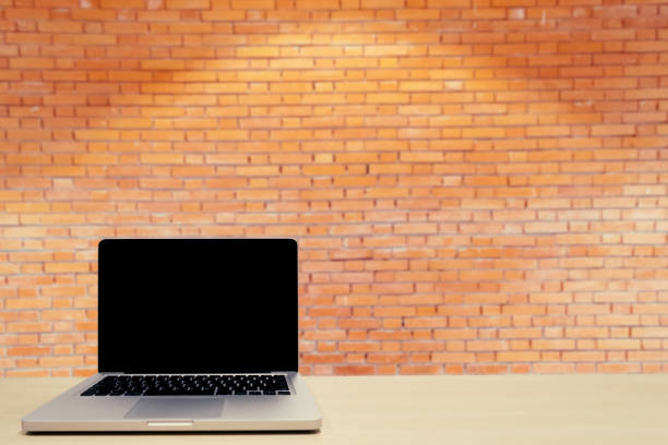 istock blank screen laptop on wooden table with retro red brick wall blurred background 687658782