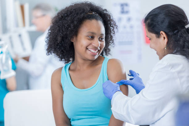 Doctor places bandage on patient's arm Female doctor puts a bandage on teenage girl's arm after receiving immunization. girl patient stock pictures, royalty-free photos & images