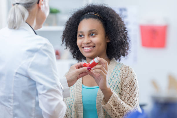 African American teenage girl learns to use inhaler African American teenage girl with asthma learns to use inhaler. A senior female doctor is instructing her on the proper use of the inhaler. Asthmatic stock pictures, royalty-free photos & images