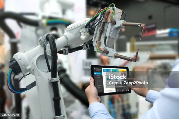 Engineer Hand Using Tablet Heavy Automation Robot Arm Machine In Smart Factory Industrial With Tablet Real Time Monitoring System Application Industry 4th Iot Concept Stock Photo - Download Image Now