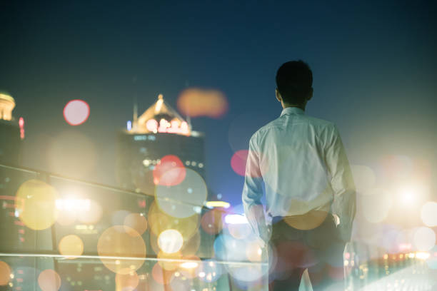 istock Businessman looking at city at night 687664350