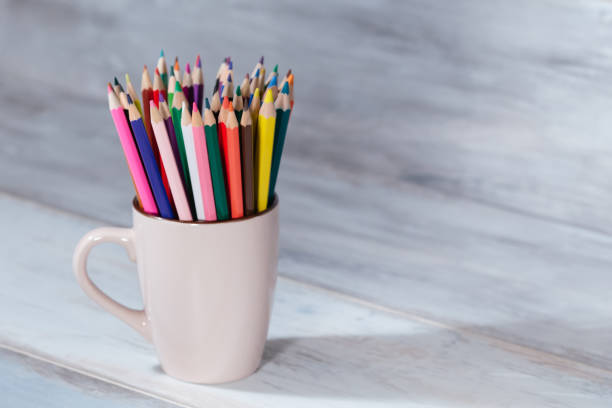 istock Stack of colored pencils in a glass on wooden background 687664386