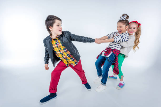 istock side view of laughing girls pulling up boy on grey 687664526