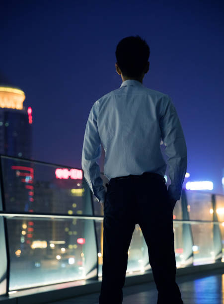 istock Businessman looking at city at night 687674762