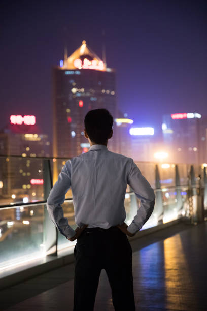 istock Businessman looking at city at night 687675224