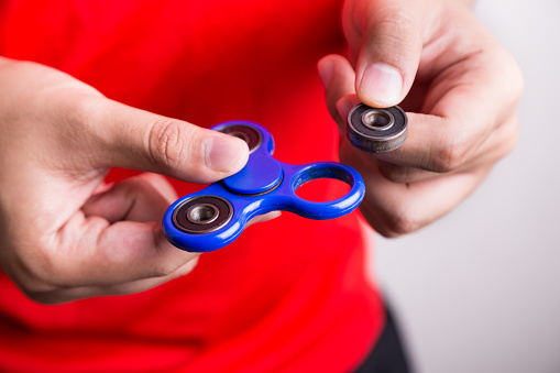 Person holding dislodged weight from fidget spinner. Hazard and dangerous for child kids.