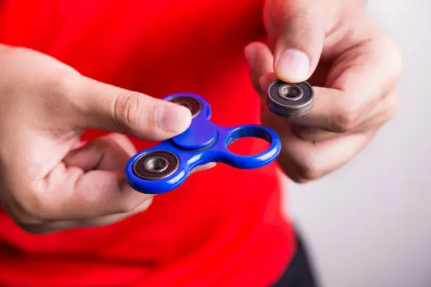 Photo of Person holding dislodged weight from fidget spinner, dangerous for kids