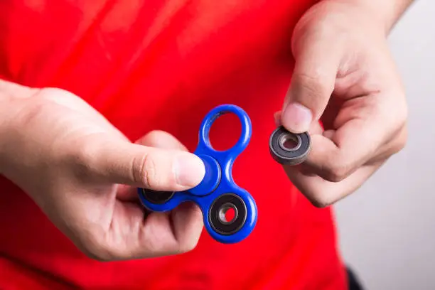 Photo of Person holding dislodged weight from fidget spinner, dangerous for kids